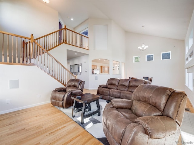 living room with a chandelier, wood finished floors, high vaulted ceiling, stairway, and baseboards