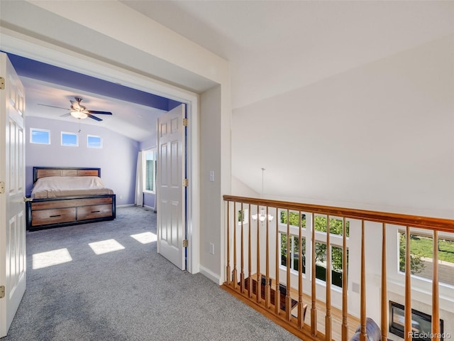 hallway with vaulted ceiling, carpet flooring, and baseboards