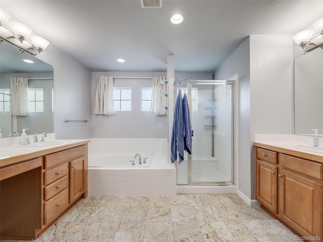 full bathroom with a stall shower, a bath, two vanities, and recessed lighting
