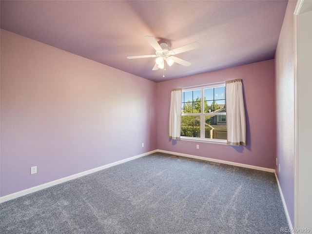 spare room featuring dark colored carpet, baseboards, and a ceiling fan