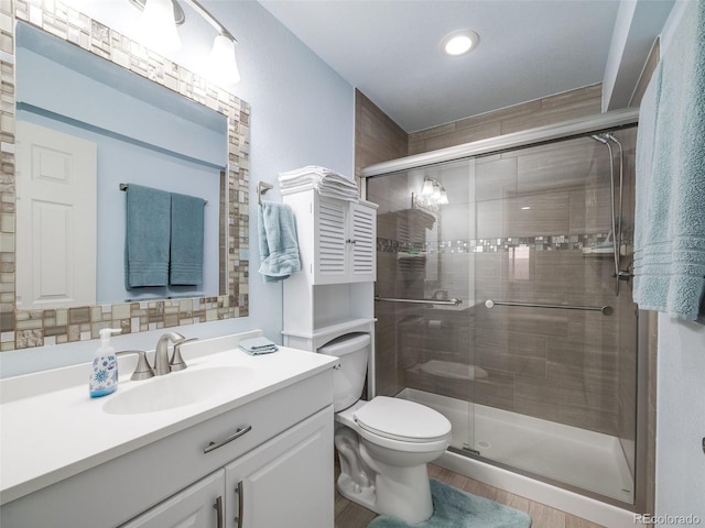 full bath featuring a shower stall, vanity, toilet, wood finished floors, and recessed lighting