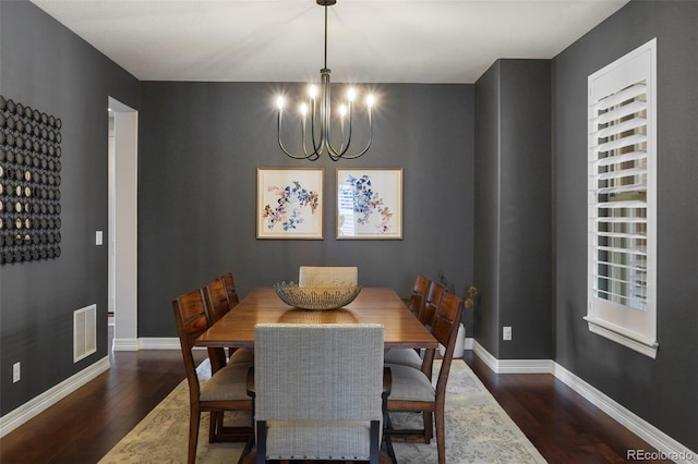 dining space featuring a chandelier, baseboards, visible vents, and wood finished floors