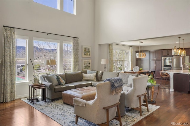 living area featuring dark wood-type flooring, a mountain view, a high ceiling, and an inviting chandelier