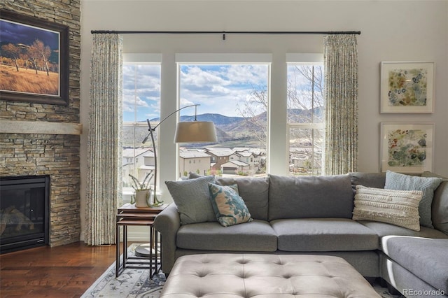 living area with a stone fireplace, a mountain view, and wood finished floors