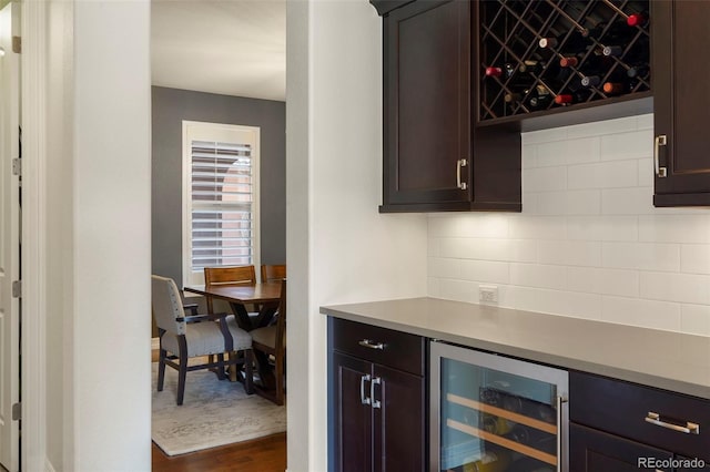bar featuring beverage cooler, baseboards, dark wood-type flooring, a dry bar, and backsplash