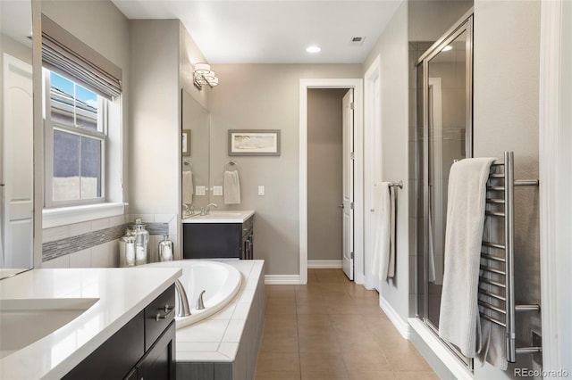 bathroom featuring a garden tub, tile patterned flooring, a stall shower, two vanities, and a sink