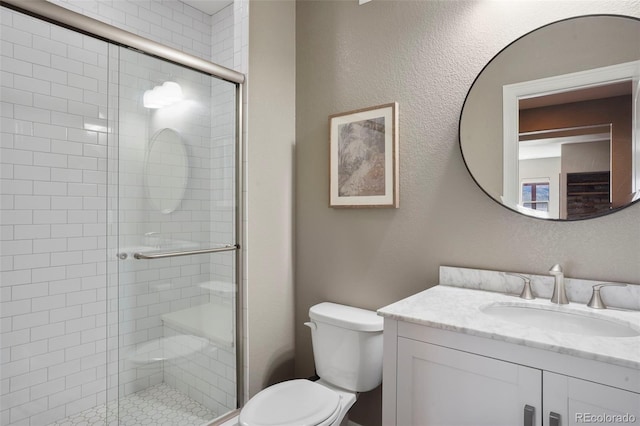 full bathroom featuring vanity, a stall shower, and toilet