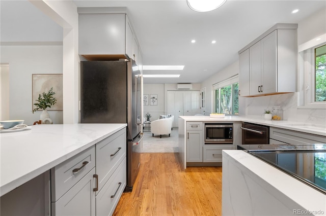 kitchen featuring stainless steel appliances, gray cabinetry, light wood finished floors, a wall unit AC, and recessed lighting