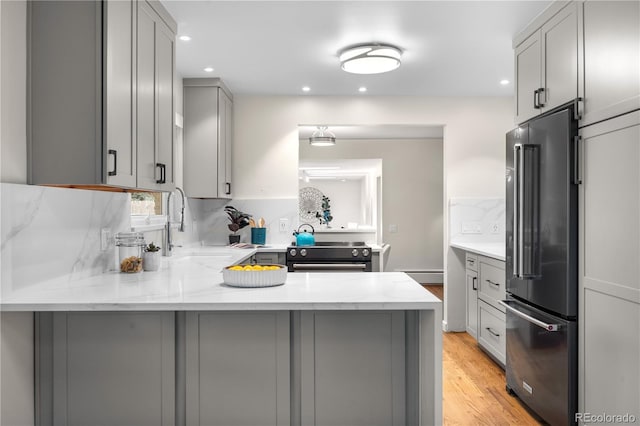kitchen featuring high end fridge, gray cabinetry, electric stove, a peninsula, and backsplash