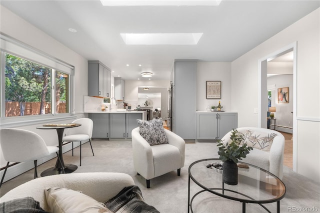 living room with healthy amount of natural light, a skylight, baseboard heating, and light colored carpet