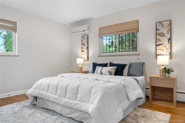 bedroom with an AC wall unit, wood finished floors, and a baseboard radiator