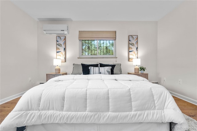 bedroom with an AC wall unit, wood finished floors, and baseboards