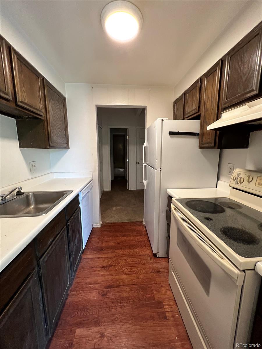 kitchen with white appliances, ventilation hood, dark brown cabinetry, dark hardwood / wood-style floors, and sink