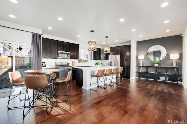 kitchen with stainless steel appliances, a kitchen breakfast bar, dark brown cabinetry, a kitchen island, and decorative light fixtures