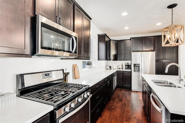 kitchen featuring appliances with stainless steel finishes, dark hardwood / wood-style floors, tasteful backsplash, sink, and hanging light fixtures