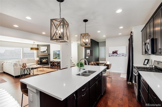 kitchen featuring pendant lighting, an island with sink, sink, dark hardwood / wood-style flooring, and stainless steel appliances