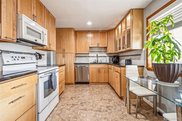 kitchen with a sink, backsplash, recessed lighting, white appliances, and glass insert cabinets