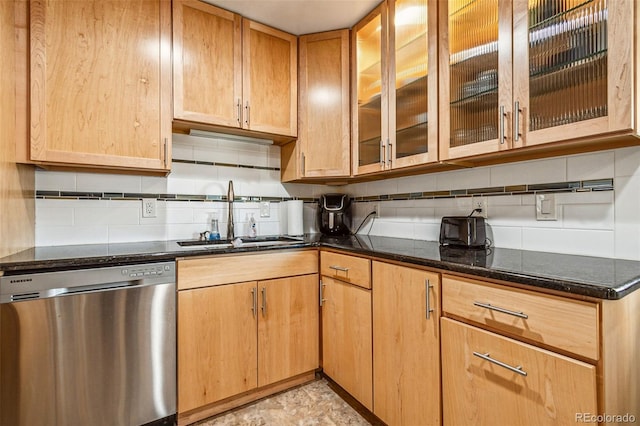 kitchen featuring stainless steel dishwasher, dark stone countertops, tasteful backsplash, and a sink