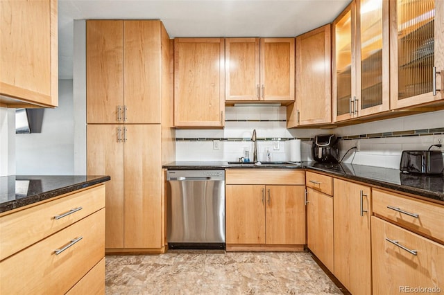 kitchen featuring glass insert cabinets, dark stone counters, decorative backsplash, stainless steel dishwasher, and a sink