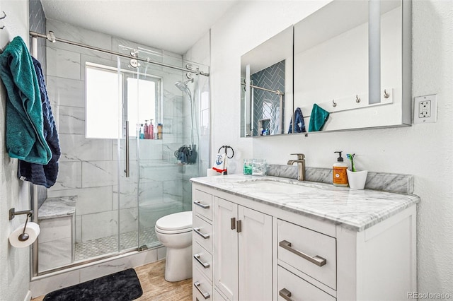 full bath with vanity, toilet, wood finished floors, and a stall shower