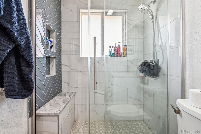 full bath with toilet, a textured wall, a stall shower, and a wealth of natural light