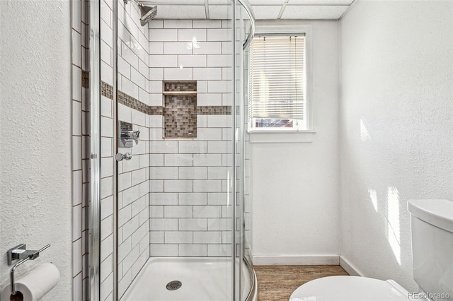 bathroom featuring toilet, baseboards, a stall shower, and a textured wall