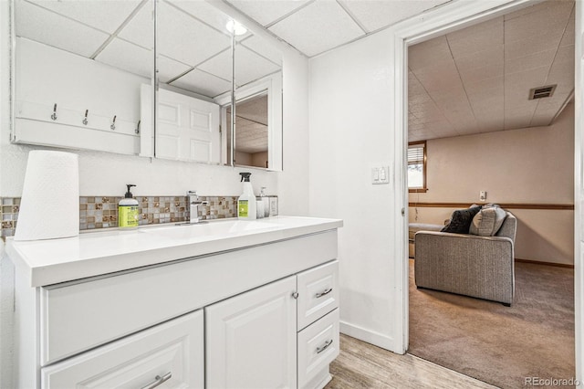 bathroom featuring visible vents, a paneled ceiling, backsplash, and vanity