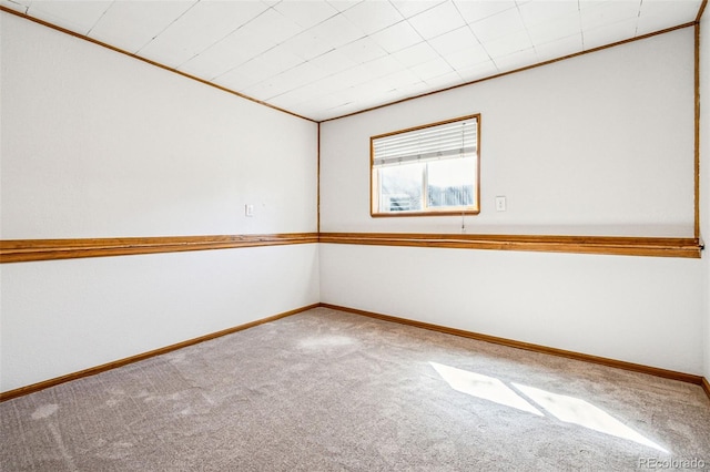 carpeted empty room featuring baseboards and ornamental molding