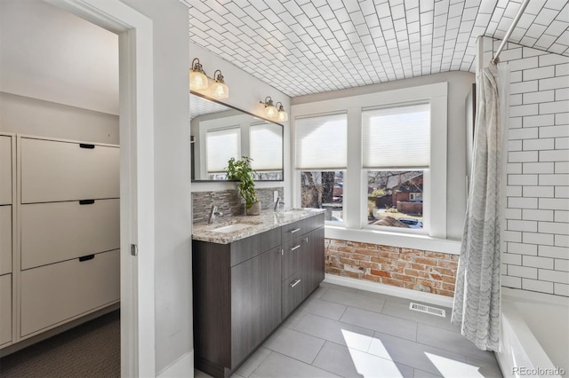 1626 Albion St, Denver, CO 80220 - bathroom with vanity, healthy amount of natural light, tile patterned floors, baseboards, and brick wall