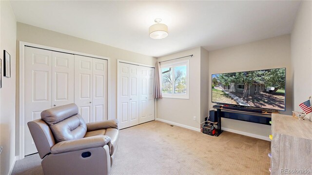 living area featuring light carpet and baseboards