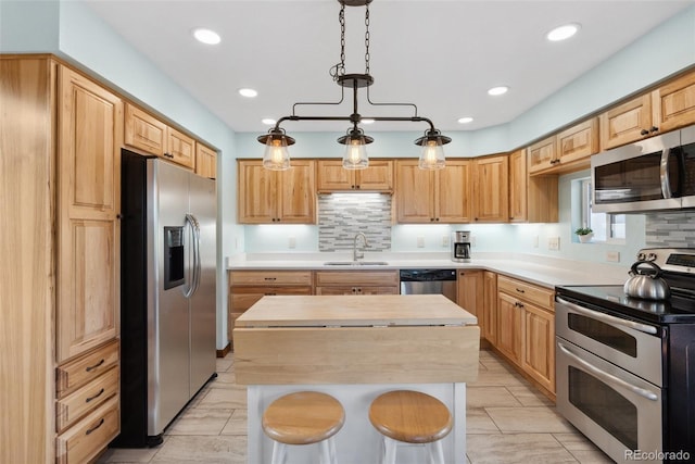 kitchen featuring a center island, stainless steel appliances, light countertops, a kitchen bar, and a sink