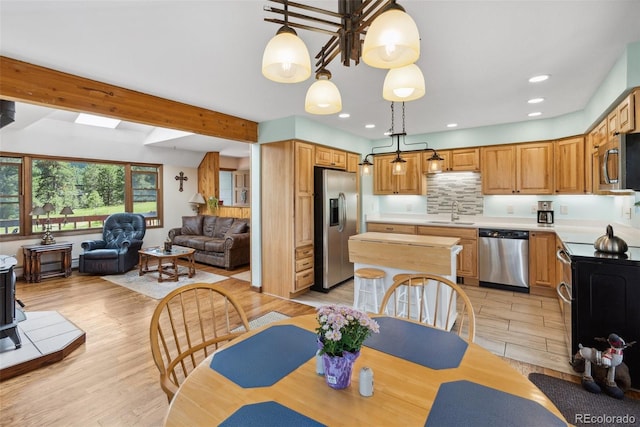 dining room with light wood finished floors, beam ceiling, and recessed lighting