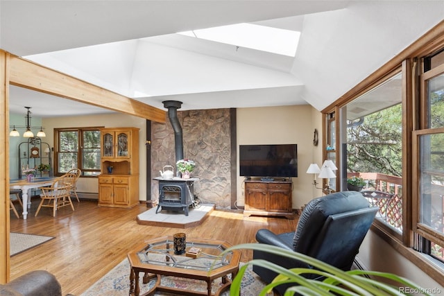 living area featuring lofted ceiling, a wood stove, and wood finished floors