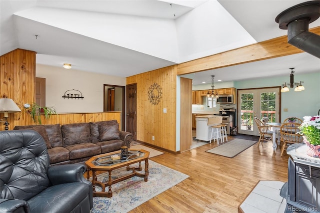 living room with light wood-style flooring, lofted ceiling, wooden walls, and an inviting chandelier