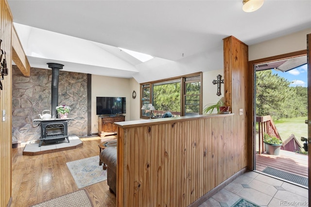 kitchen featuring light wood-type flooring, plenty of natural light, a wood stove, and vaulted ceiling