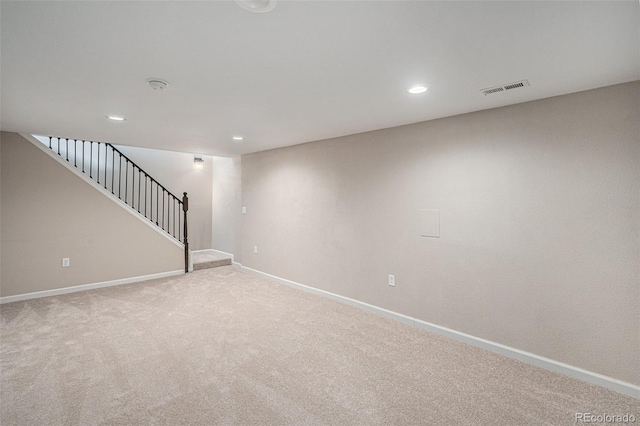 empty room featuring visible vents, baseboards, light colored carpet, stairway, and recessed lighting