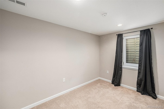 empty room with baseboards, visible vents, and light colored carpet