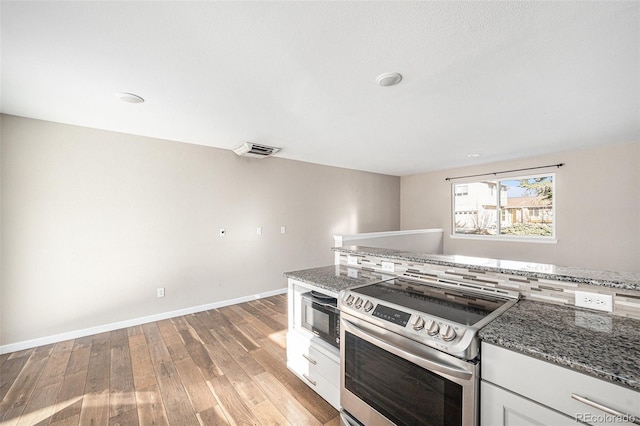 kitchen featuring light wood-type flooring, stone countertops, visible vents, and electric stove