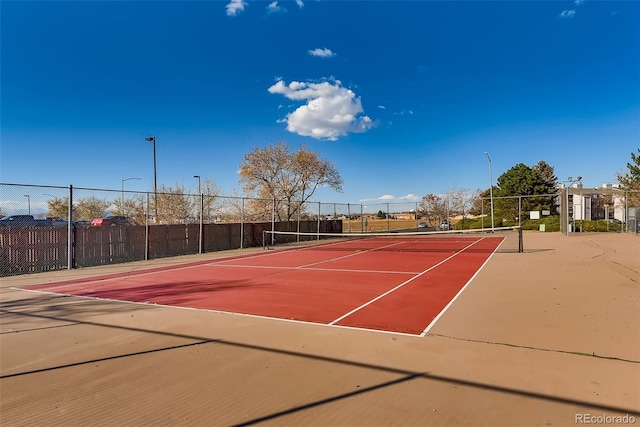 view of tennis court with community basketball court and fence