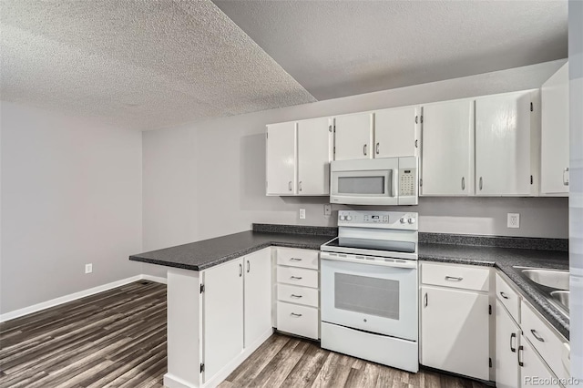 kitchen featuring white appliances, a peninsula, white cabinets, and dark wood-style flooring