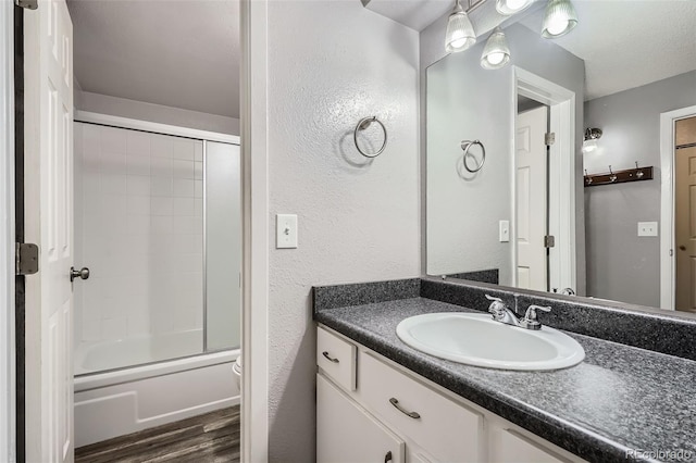 full bathroom with vanity, hardwood / wood-style flooring, enclosed tub / shower combo, and toilet