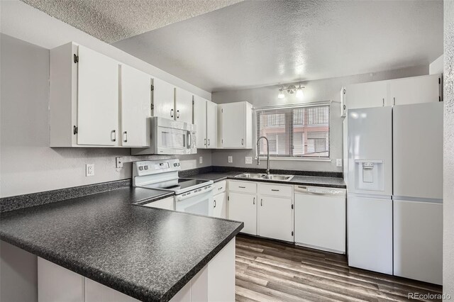 kitchen featuring a sink, white appliances, dark countertops, and a textured ceiling