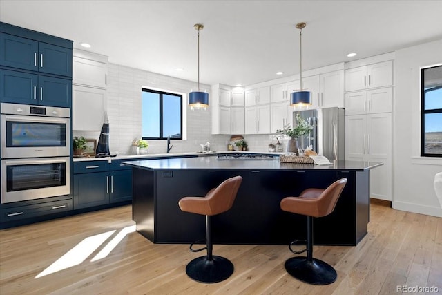 kitchen featuring stainless steel appliances, a center island, blue cabinets, and white cabinets