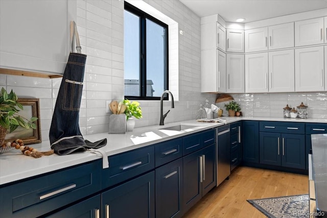 kitchen with white cabinetry, sink, blue cabinetry, and light wood-type flooring