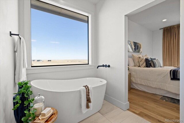 bathroom with a tub to relax in and hardwood / wood-style flooring