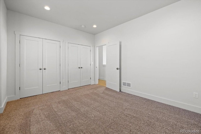 unfurnished bedroom featuring carpet and two closets