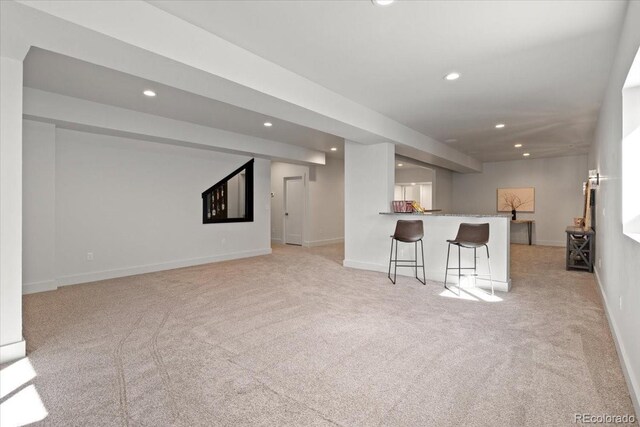 unfurnished living room featuring light colored carpet and indoor bar