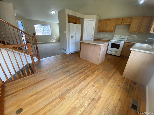 kitchen with white appliances, visible vents, a kitchen island, a sink, and light countertops