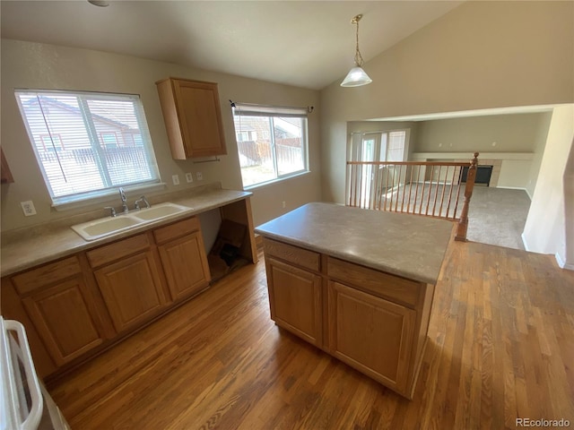kitchen with light wood-style flooring, light countertops, lofted ceiling, and a sink