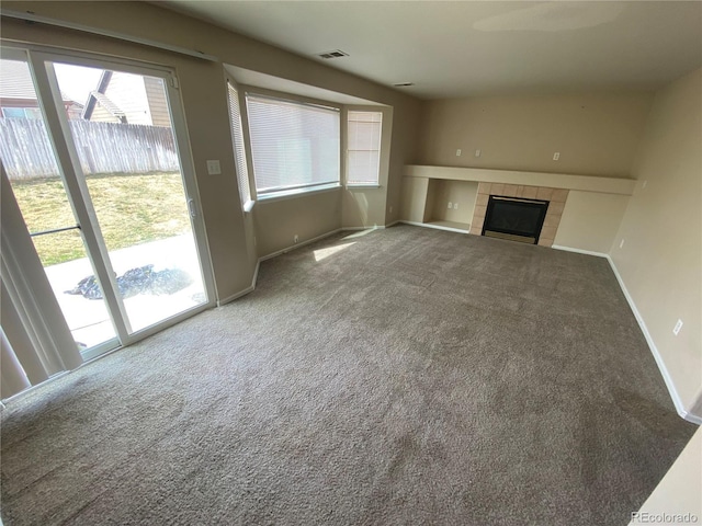 unfurnished living room featuring visible vents, a fireplace, baseboards, and carpet floors